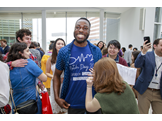 Victor Ayeni wears a t-shirt reading “Match Day 2020 – I matched in Internal Medicine at:” and smiles as a person uses a marker to fill in “Duke University."